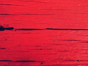 Close-up of a textured red wooden surface, perfect for vivid backgrounds and design use.